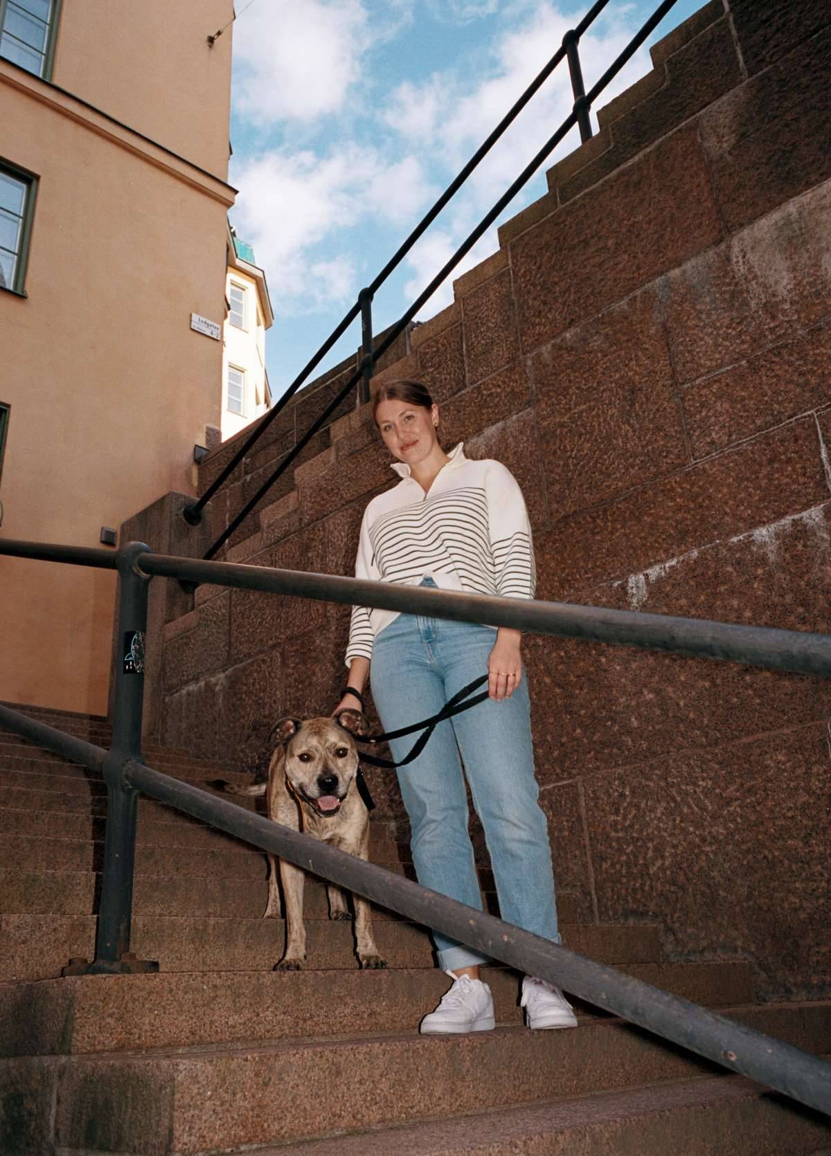 Fia Ramström står i en trappa med sin hund.